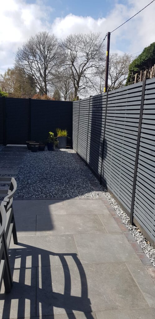 Double-slatted grey fencing with black posts and gravel boards