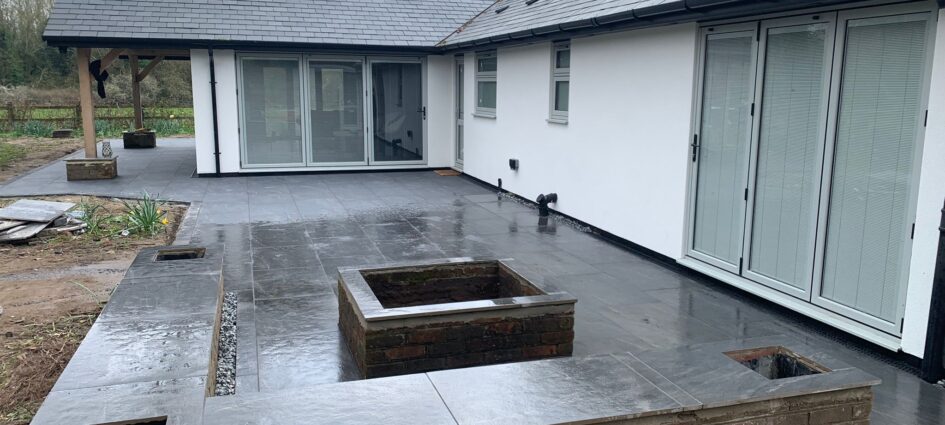 Large anthracite porcelain patio with charcoal regular block edging and turf in Wokingham