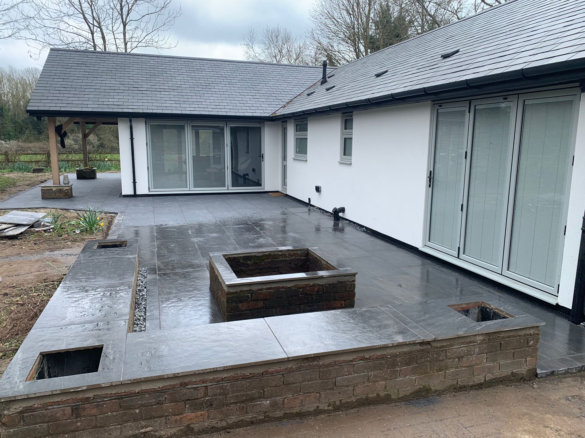 Large anthracite porcelain patio with charcoal regular block edging and turf in Wokingham